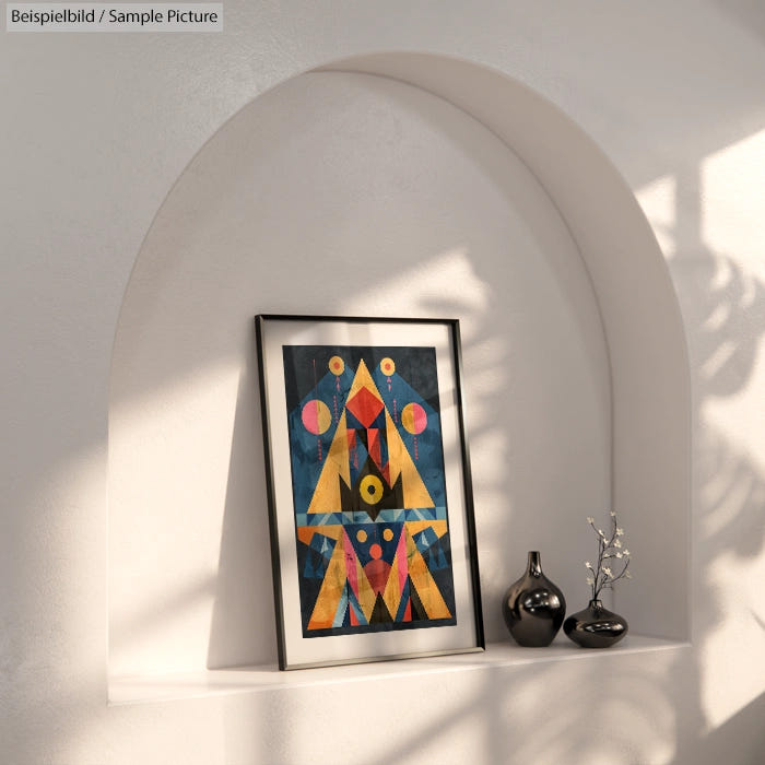 Framed abstract geometric art in a niche with shadows, next to a small dark vase and dried flowers.