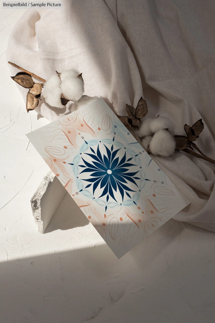 Abstract art print with blue floral design on draped fabric with cotton and dried leaves.