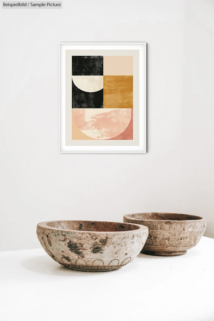 Modern abstract artwork in frame above two decorative wooden bowls on a white background.