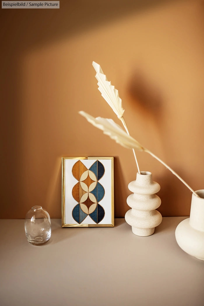 Minimalistic table decor with abstract framed art and vases against a warm brown wall.