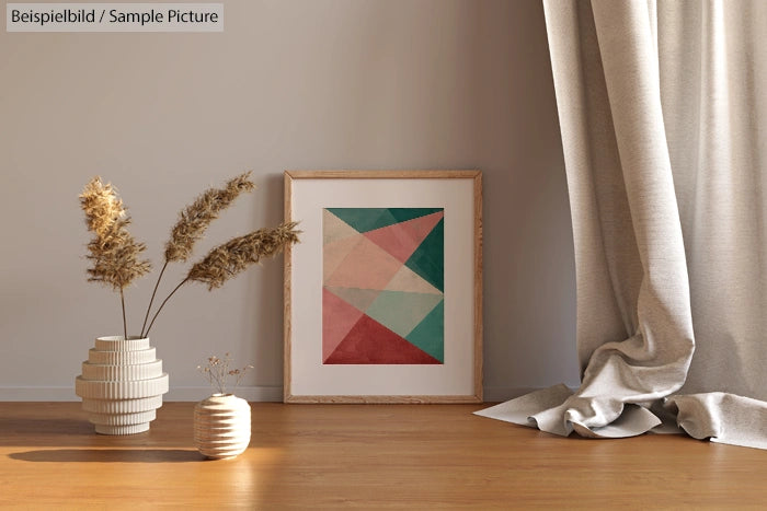 Framed geometric art on floor beside vases and curtain in interior room with wooden floor.