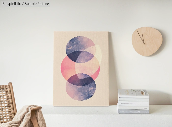 Geometric abstract art with overlapping circles, displayed on a white shelf with decor items.