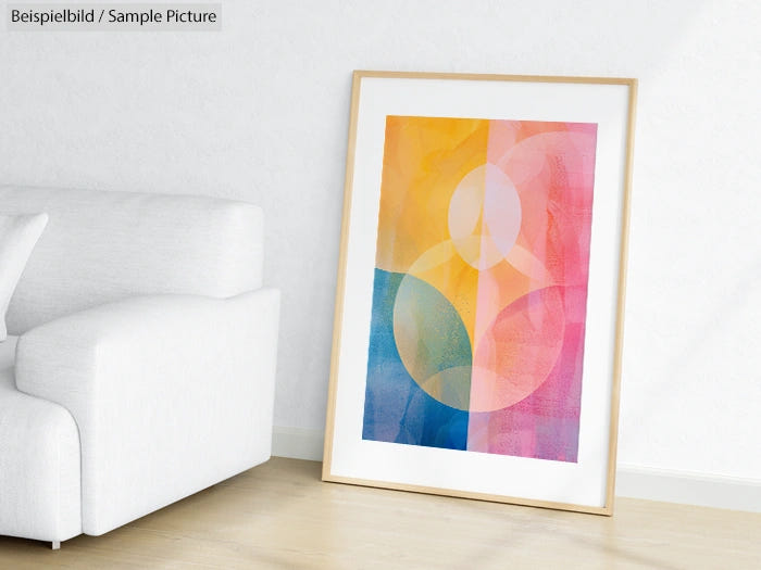 Framed abstract art with colorful geometric circles leaning against a white wall near a white sofa.