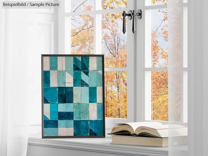 Abstract teal and white geometric painting near a window with autumn view beside an open book.