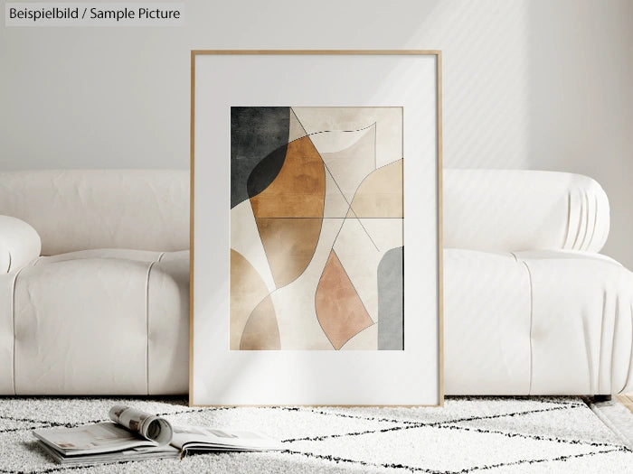 Framed abstract art with geometric shapes on wall above white sofa, beige and gray tones.