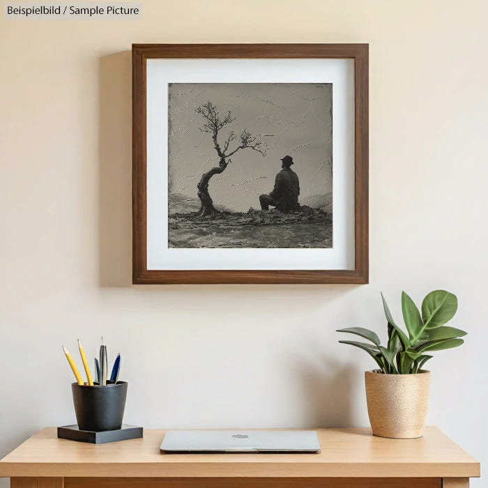 Minimalist workspace with framed tree painting, laptop, plant, and pencils on a wooden desk.