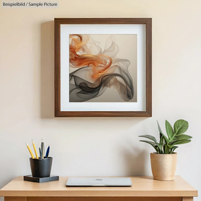 Framed abstract art with orange and black swirls on beige wall above desk with potted plant and pen holder.