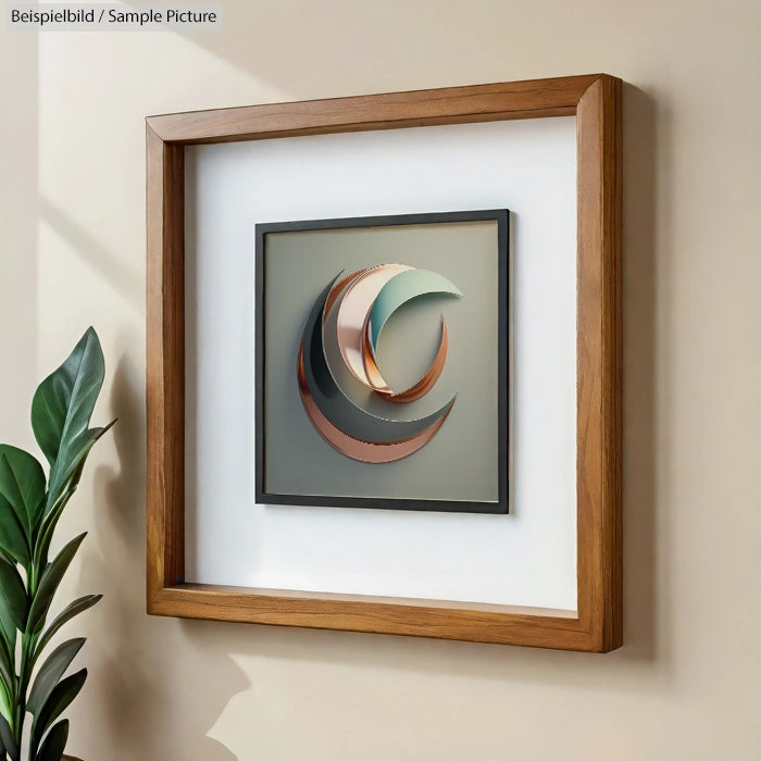 Framed modern geometric artwork with crescent shapes in earthy tones, hung on a wall next to a green plant.