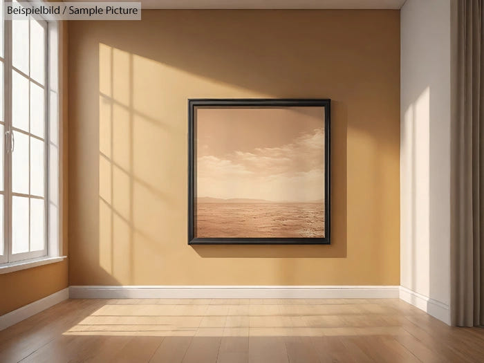 Framed desert landscape photo on a beige wall in sunlit room with wooden floor.