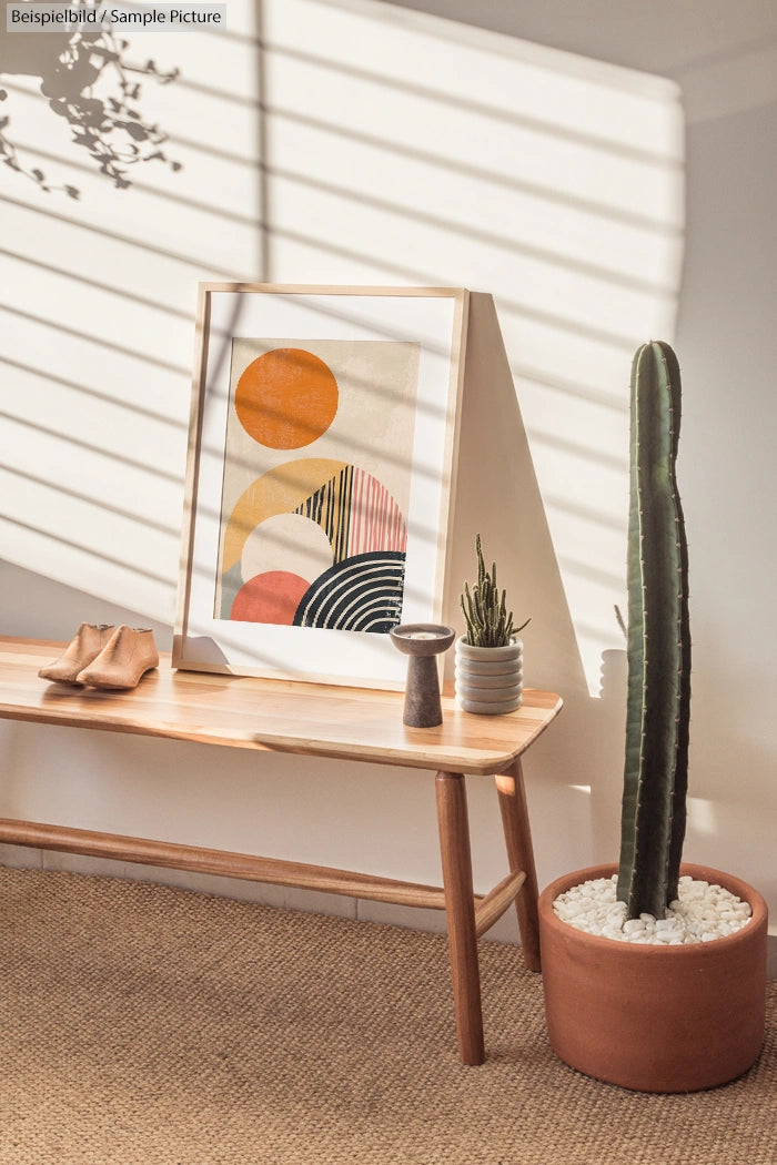 Minimalist room with abstract art, a wooden bench, and a potted cactus under striped sunlight.