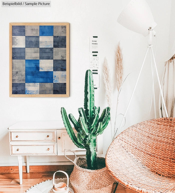 Cozy living room with wicker chair, cactus plant, abstract blue artwork, white lamp, and wooden side table.