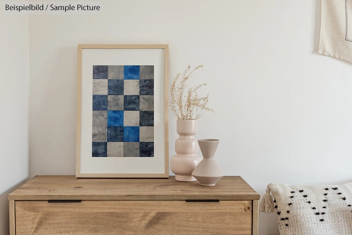 Minimalistic room with a wooden table, abstract checkered artwork, and two vases with dried flowers.