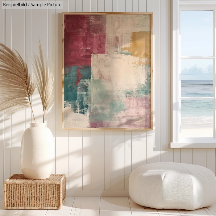 Abstract painting with red, teal, and beige blocks in a bright beach-themed room with a large window view of the sea.