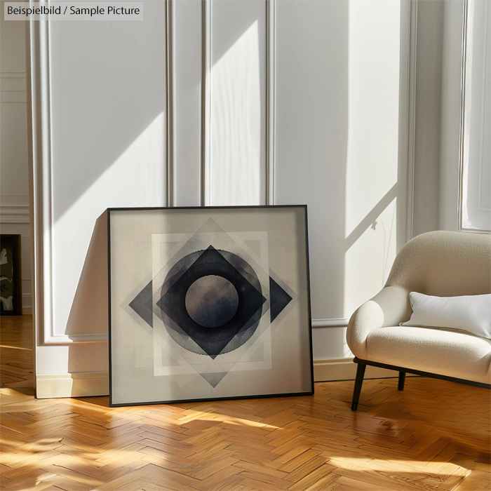 Modern art print with geometric shapes leaning against a white paneled wall beside a white armchair on wooden flooring.