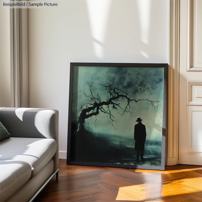 Framed artwork of a silhouette under a gnarled tree, leaning against a wall near a sofa in a well-lit room.