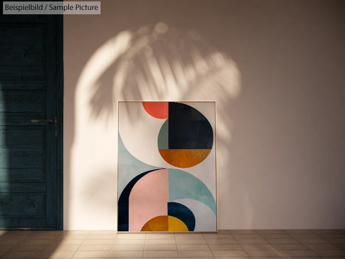 Geometric abstract painting with circles and arcs on floor against a shadowed wall.