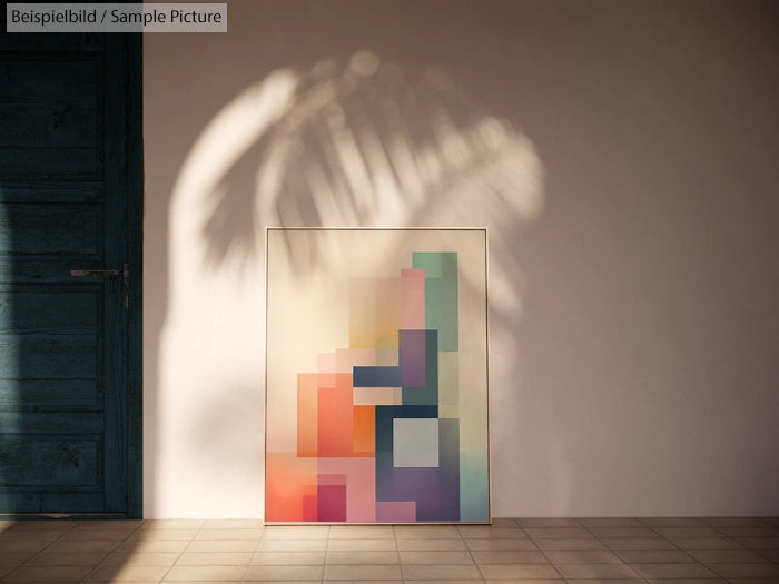 Colorful geometric abstract art leaning against a sunlit wall, with a shadow of a palm leaf on the background.