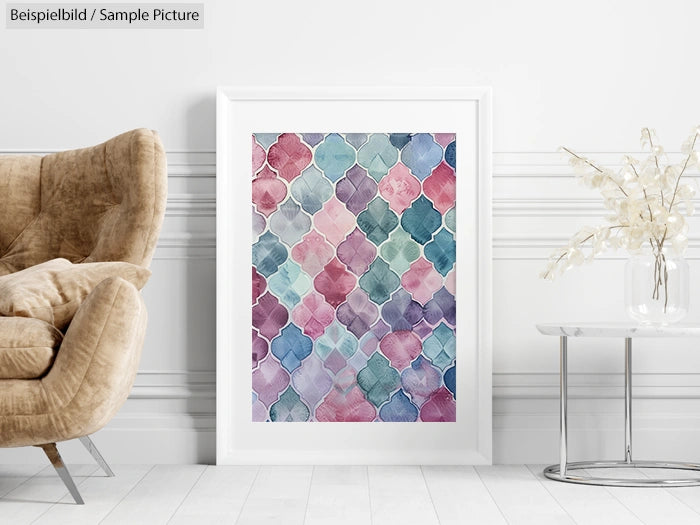 Framed abstract art in pink, blue, and green hues on wall next to beige chair and dry plant in glass vase.