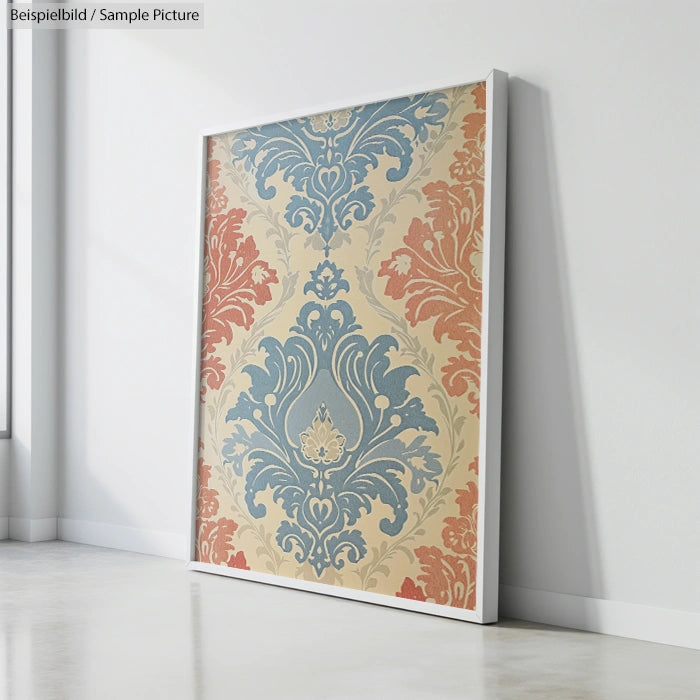 Framed artwork with ornate blue, red, and beige floral patterns leaning against a white wall.