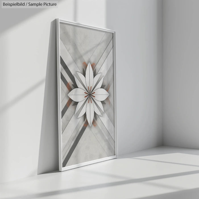 Modern framed artwork with abstract geometric design and star-like flower pattern, leaning against a white wall.