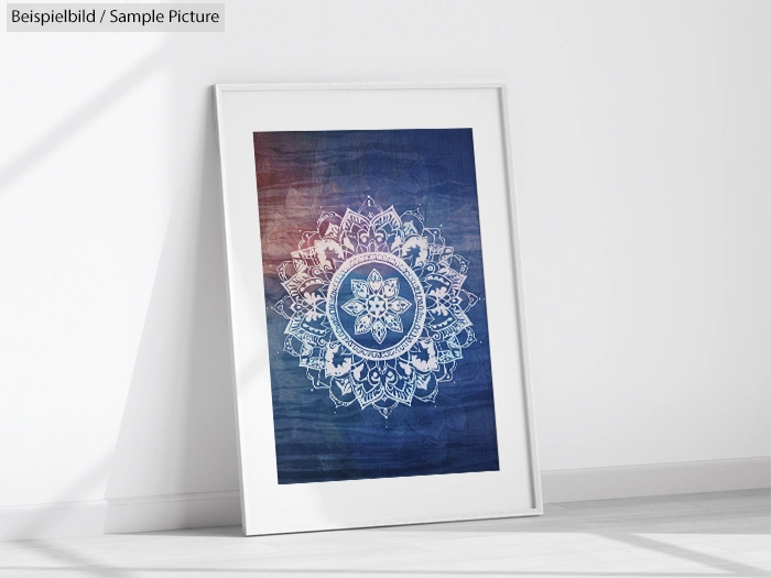 Framed mandala artwork with intricate white patterns on a blue background, leaning against a white wall.