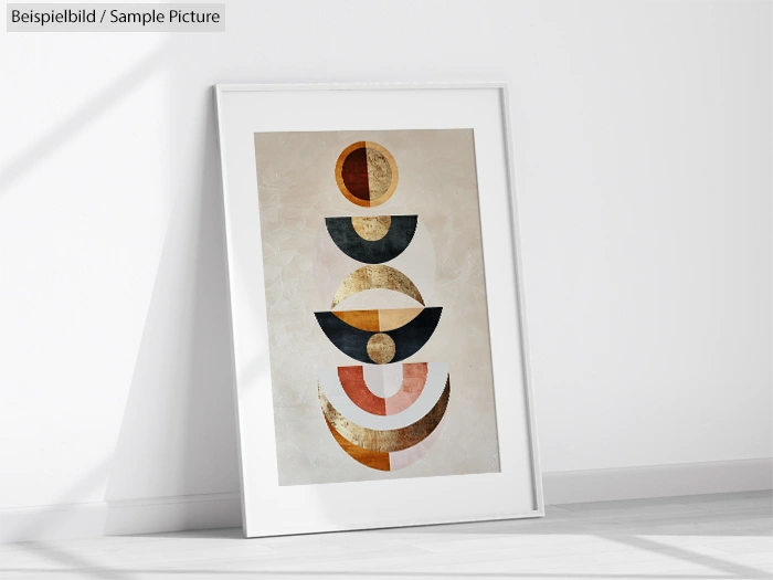 Framed abstract geometric artwork with semi-circles in earthy tones, leaning against a white wall.