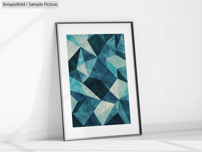 Framed abstract art with geometric blue and teal shapes, leaning against a white wall in a minimalist room.