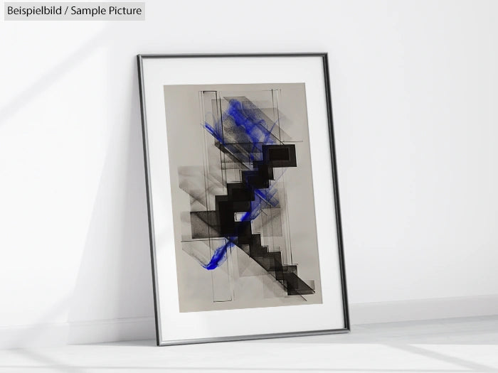 Framed abstract art with black geometric shapes and blue brushstrokes leaning against a white wall.