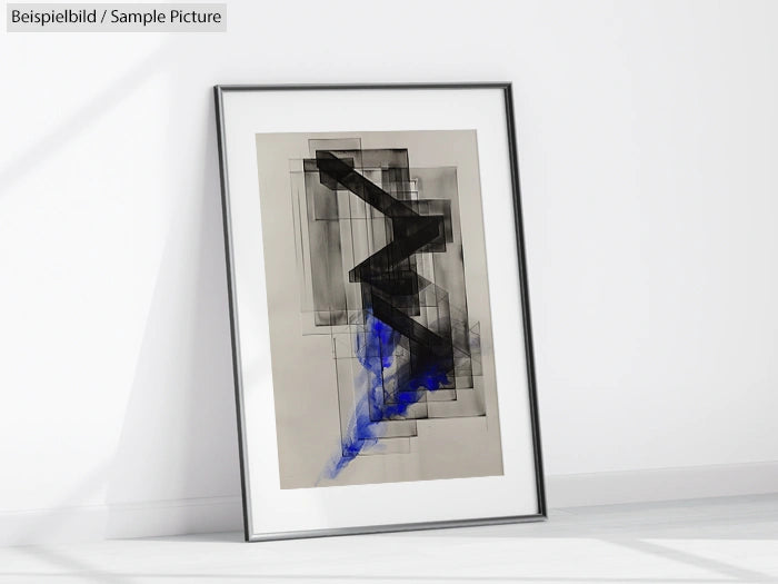 Framed abstract artwork with black geometric shapes and blue accents on a light background, leaning against a white wall.