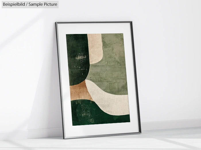 Framed abstract art with green, beige, and brown shapes leaning against a white wall.