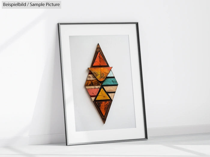 Framed geometric wooden artwork with colorful triangles, leaning against a white wall.