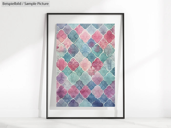 Framed geometric watercolor print with pink, blue, and green pattern on white wall.