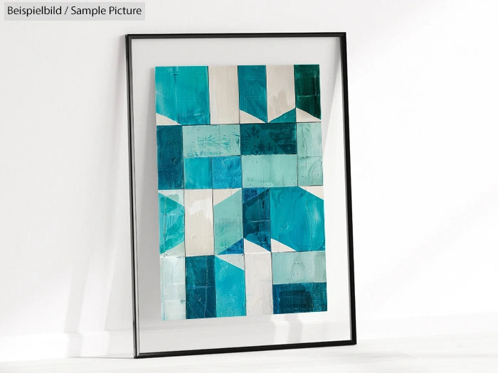 Framed geometric abstract art with blue and white squares leaning against a white wall.