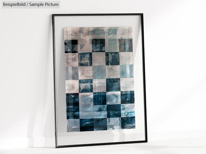 Framed abstract artwork with a blue and gray geometric grid pattern on a white wall.