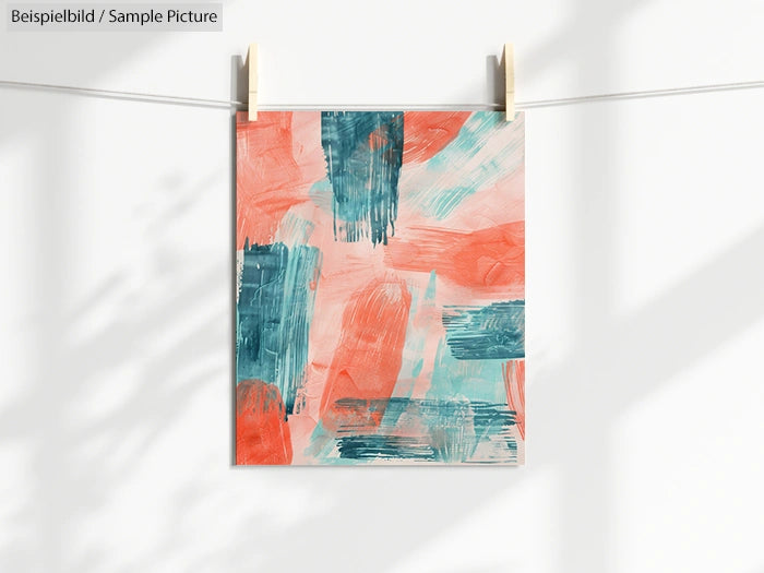 Abstract painting with orange and teal brushstrokes hanging on a line.