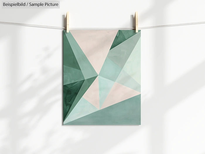 Geometric art print with shades of green and beige, hanging on a line with clothespins.