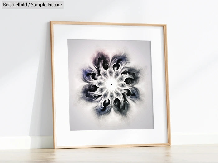 Framed abstract art with a symmetrical design using dark and light shades on a white wall.