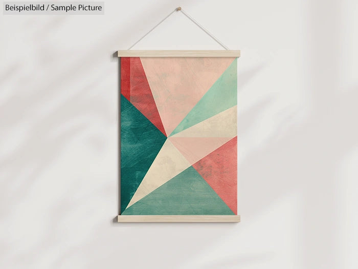 Abstract geometric wall art with red, green, and beige triangles, hanging on a white wall.