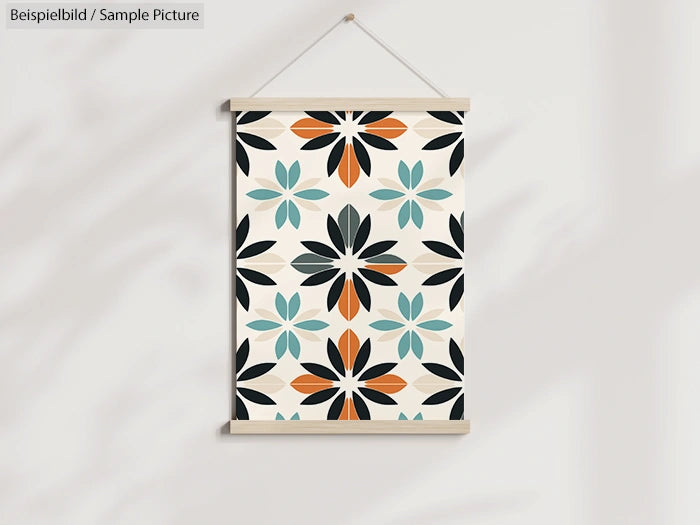 Wall poster with geometric floral pattern in black, orange, and teal hues, hanging on a white wall.