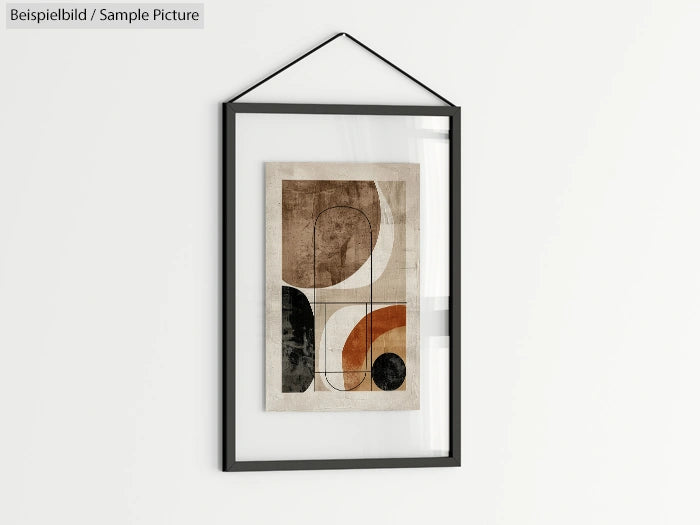 Framed abstract art with geometric shapes in black, white, and orange tones, hanging on a white wall.