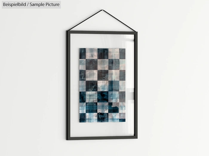 Framed abstract artwork with blue and gray geometric patterns, hanging on a white wall.