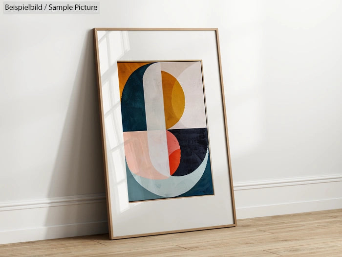 Framed abstract art with geometric shapes in yellow, blue, red, and white, leaning against a white wall on wood floor.