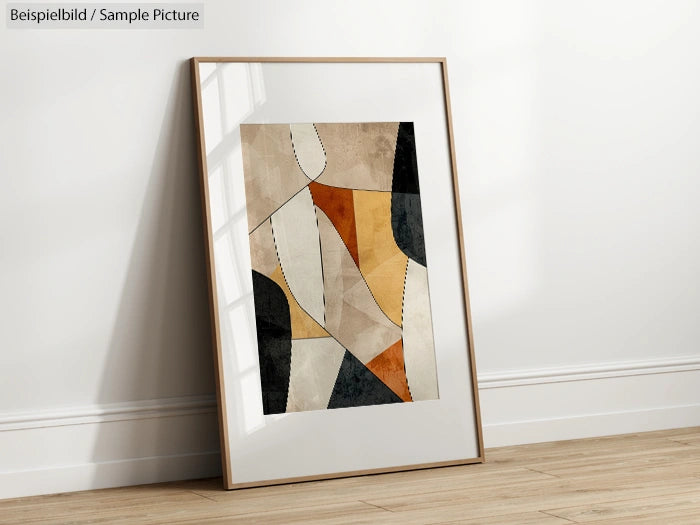 Framed abstract art with geometric shapes and earth tones on a wooden floor with sunlight casting shadows.