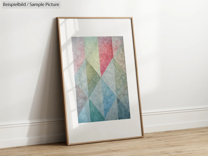 Framed geometric abstract art with red, green, and blue triangles leaning against a white wall.