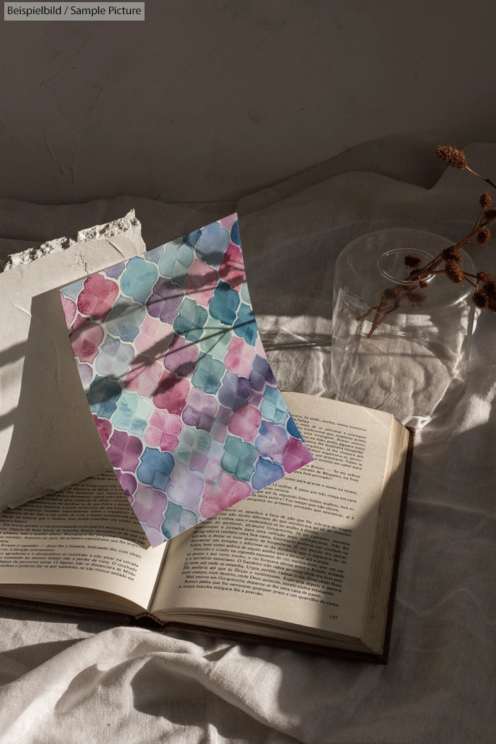 Watercolor hexagon pattern on paper, placed over an open book in soft, natural lighting with dried plants nearby.