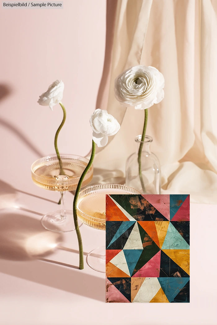 Two champagne glasses with white flowers and a colorful geometric painting in a softly lit setting.