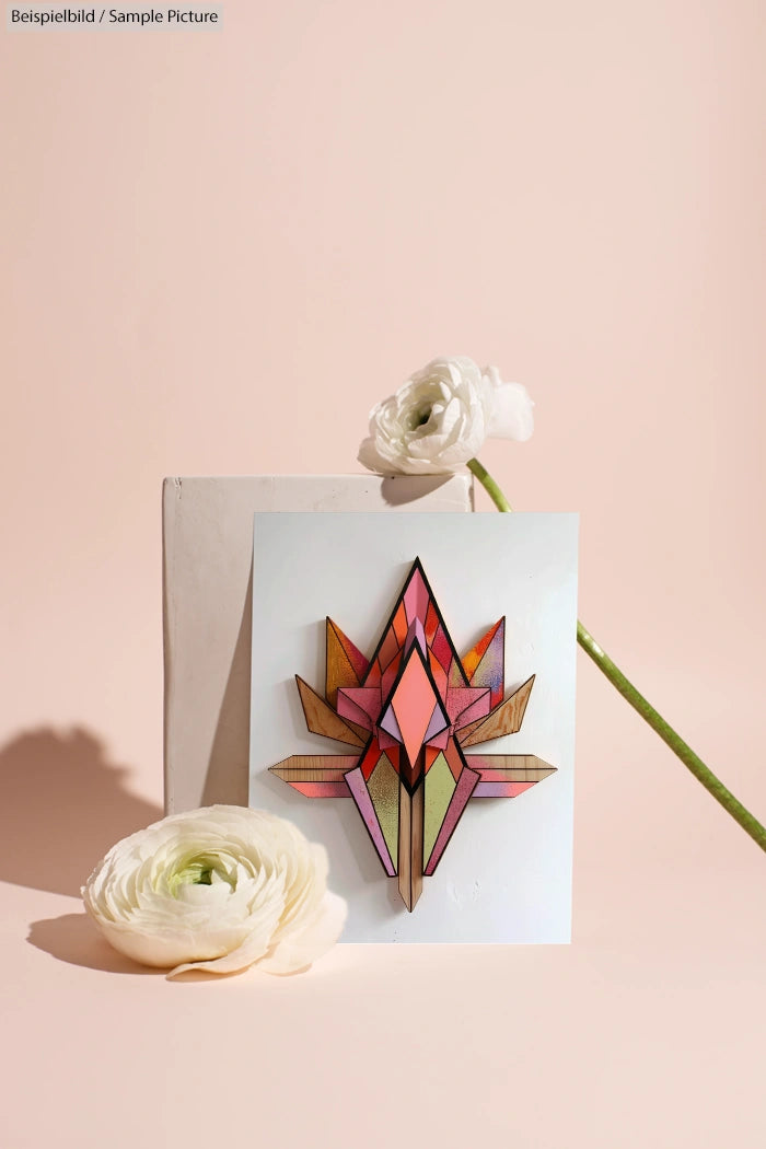 Geometric artwork with pastel hues beside white flowers on a peach background.