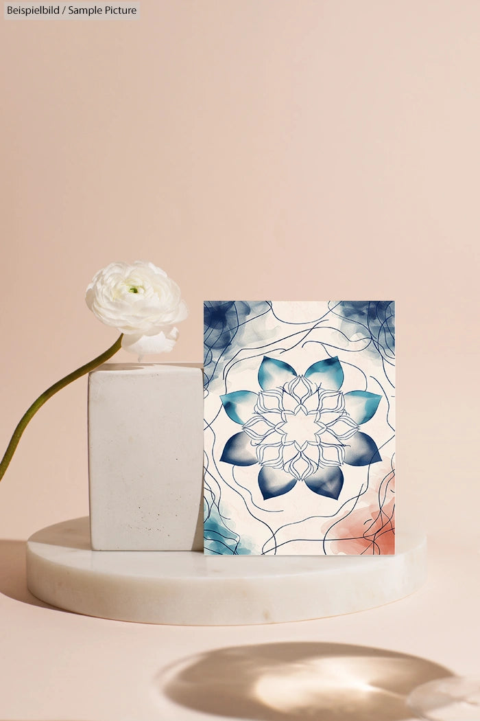 Decorative card with blue floral design on a geometric stand with a white flower in minimalistic setting.