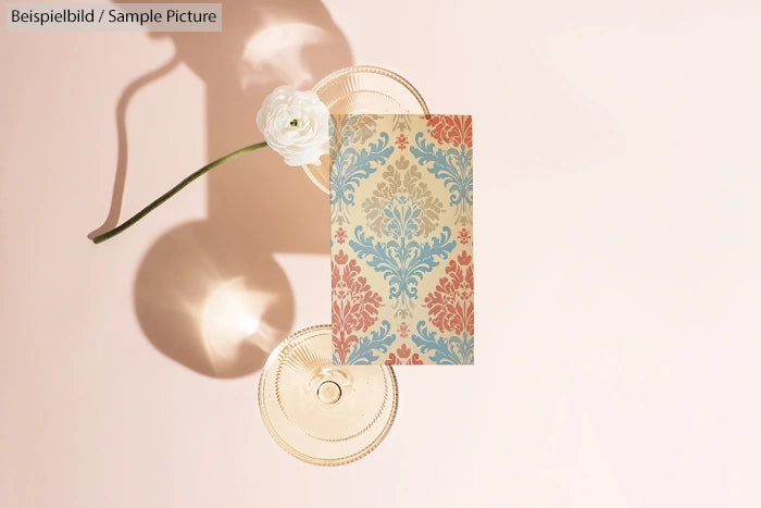 Decorative patterned card with a white flower on a pale pink background with round glass impressions.