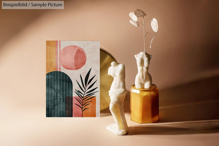 Abstract art print with geometric shapes next to two torso sculptures against a beige background.